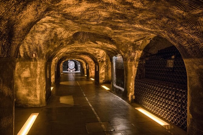 A lit tunnel through the chalk, bottles in the side bays and a cask at its end