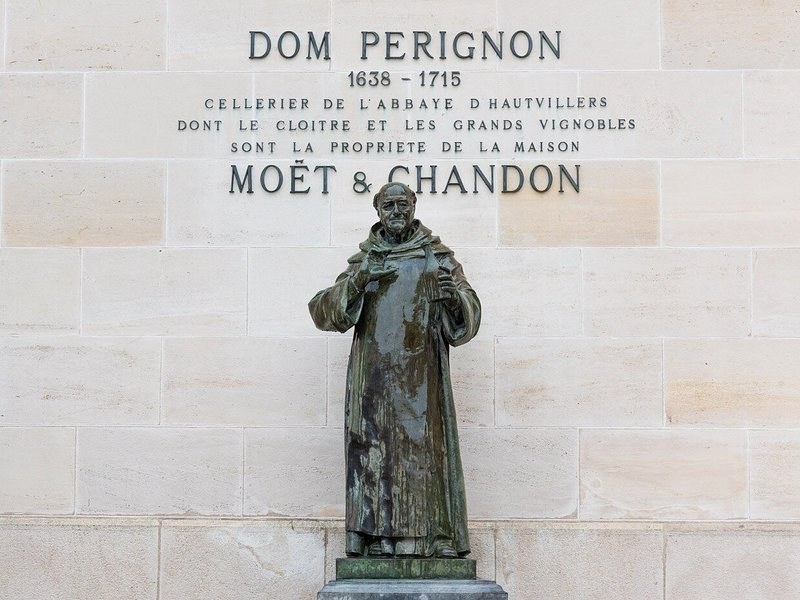 The statue of Dom Pérignon before a carved inscription naming him cellarer of the abbey of Hautvillers