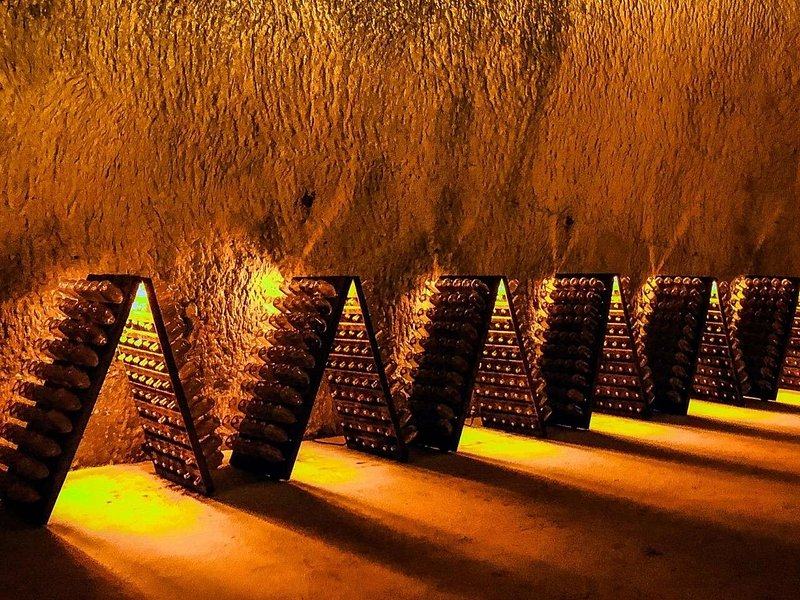 Riddling racks of bottles lit from below along a rough chalk gallery